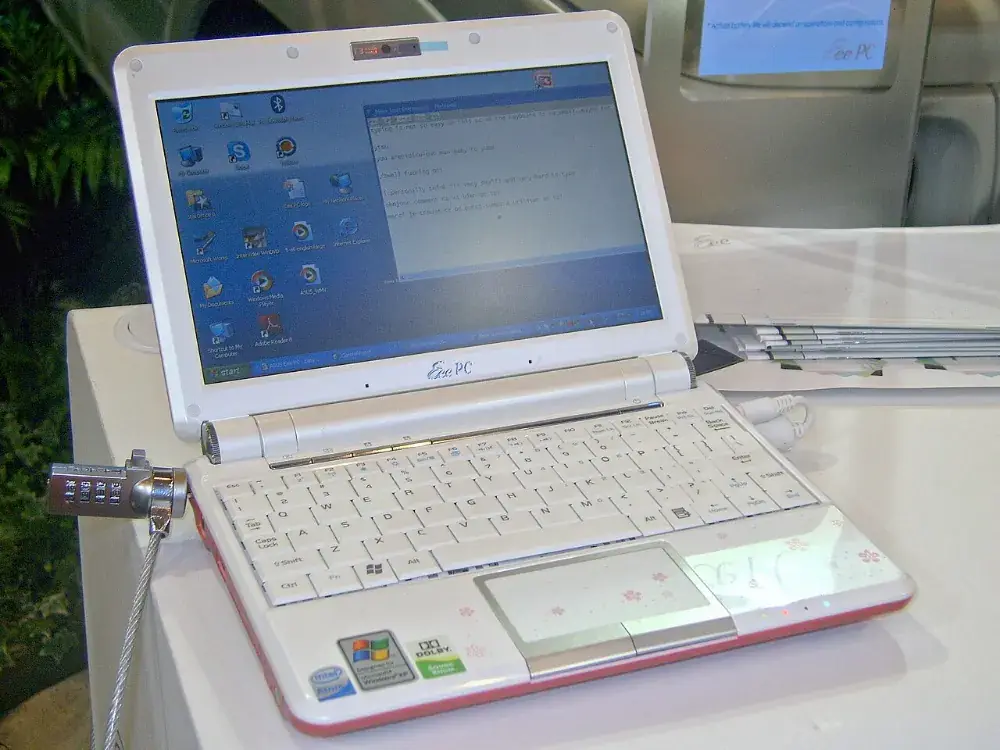 A small white Asus Eee PC 901 netbook open on a display stand, showing a Windows XP style desktop