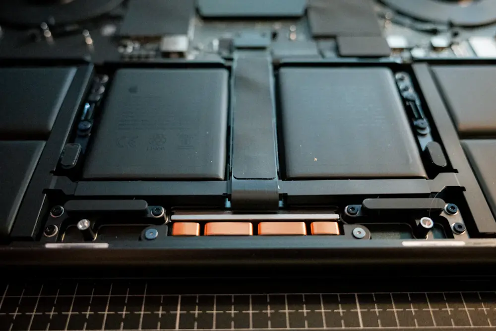 Inside of an opened laptop showing two large black lithium-ion battery cells with copper connectors