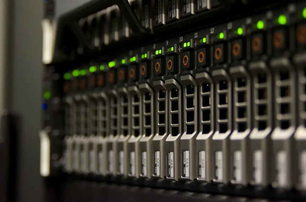 Close-up of a rack of servers in a data center with rows of drive bays and glowing green status lights